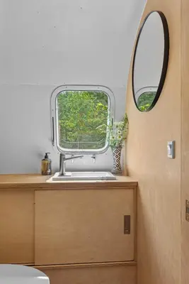 a bathroom with a round window and a sink at Sunlit Airstream in Trees with Expansive Deck Nature Views in De Lancey