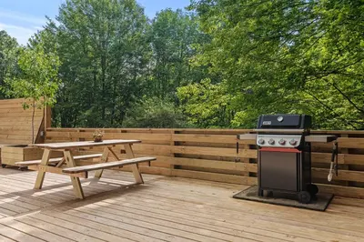 a grill and a picnic table on a deck at Sunlit Airstream in Trees with Expansive Deck Nature Views in De Lancey