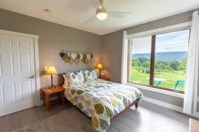 a bedroom with a bed and a large window at Spectacular Buckleberry View EV Recharge Hot Tub Fireplace Jacuzzi in Spring Mills