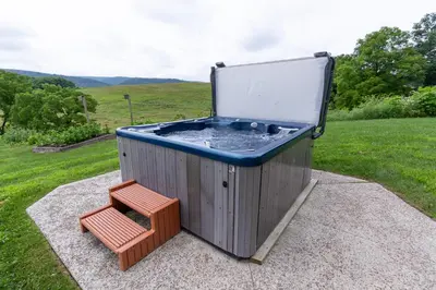 a hot tub and a bench in a field at Spectacular Buckleberry View EV Recharge Hot Tub Fireplace Jacuzzi in Spring Mills