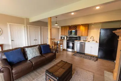 a living room with a brown couch and a kitchen at Spectacular Buckleberry View EV Recharge Hot Tub Fireplace Jacuzzi in Spring Mills