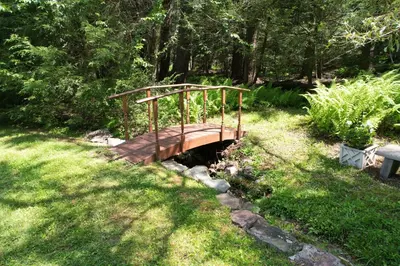 a wooden bridge over a stream in a park at Catskills Getaway 3BR Retreat with Media Room, Near Casino, Bethel Woods and More in Glen Wild