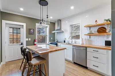 a kitchen with white cabinets and a wooden counter top at Welcome to The Lux Collective a Spacious 5-Bedroom House close to Stadiums, Universities, Center City & more! in Philadelphia