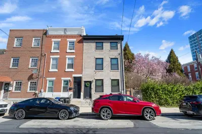 two cars parked in a parking lot in front of a building at Welcome to The Lux Collective a Spacious 5-Bedroom House close to Stadiums, Universities, Center City & more! in Philadelphia
