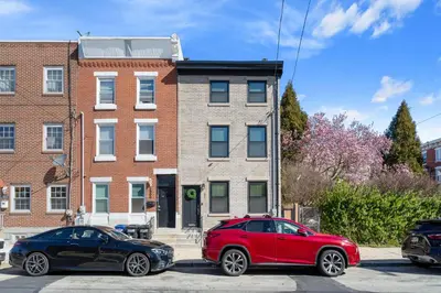 two cars parked in front of a brick building at Welcome to The Lux Collective a Spacious 5-Bedroom House close to Stadiums, Universities, Center City & more! in Philadelphia