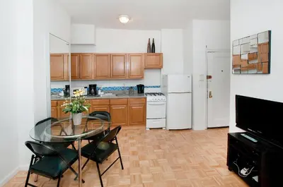 a kitchen with a glass table and chairs and a refrigerator at Mid Town East Street Apartments Next to Times Square in New York