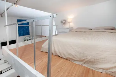 a white bedroom with a bed and a staircase at Mid Town East Street Apartments Next to Times Square in New York