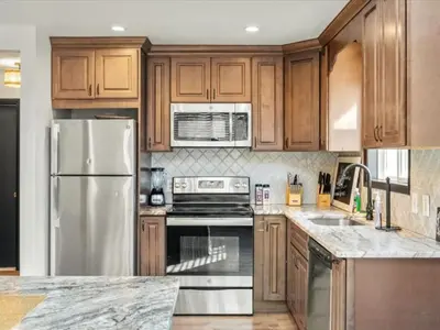 a kitchen with wooden cabinets and stainless steel appliances at Memorabile Getaway Fire-Pit and Entrainment Area in Long Pond