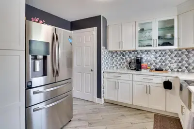 a kitchen with white cabinets and a stainless steel refrigerator at 5 Mi to Dtwn Newark Hillside Vacation Rental in Hillside