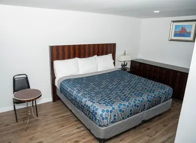 a bedroom with a bed and a table and a chair at Rainbow Motel in Douglassville