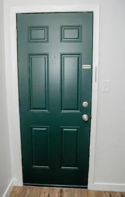 a green door in a room with a wooden floor at Rainbow Motel in Douglassville