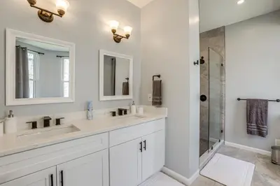 a white bathroom with two sinks and a shower at Group Getaway with Games and Patio in Philadelphia! in Philadelphia