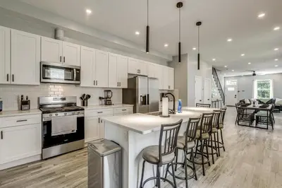 a large kitchen with white cabinets and bar stools at Group Getaway with Games and Patio in Philadelphia! in Philadelphia