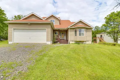 a house with a garage and a grass yard at Family Retreat with 2 Game Rooms and Deck in Long Pond in Long Pond