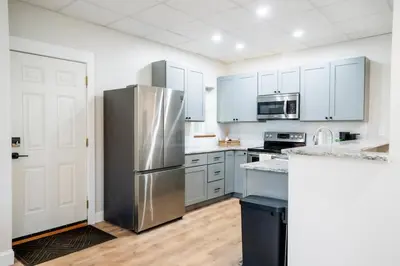 a kitchen with white cabinets and a stainless steel refrigerator at Cozy Corner Near UPMC & Downtown in Williamsport
