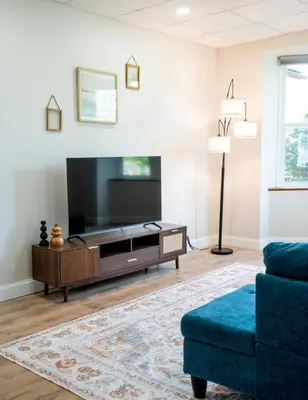 a living room with a flat screen tv and a blue couch at Cozy Corner Near UPMC & Downtown in Williamsport