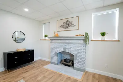 a living room with a brick fireplace and a mirror at Cozy Corner Near UPMC & Downtown in Williamsport
