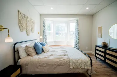 a bedroom with a bed with blue pillows and a window at Cozy Corner Near UPMC & Downtown in Williamsport