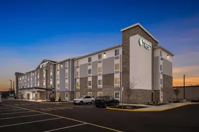 a large building with a car parked in a parking lot at WoodSpring Suites Wilmington Riverfront in Wilmington