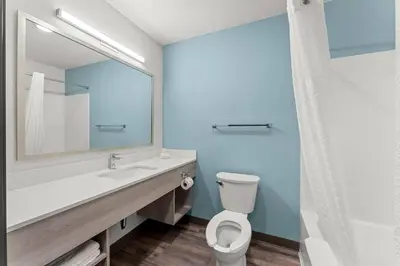 a bathroom with a toilet and a sink and a mirror at WoodSpring Suites Wilmington Riverfront in Wilmington