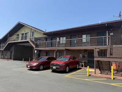 two cars parked in a parking lot in front of a building at Linden Motor Inn in Linden