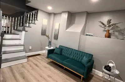 a living room with a green couch and stairs at Cozy Modern Home with Large Fenced in Backyard in Camden
