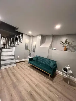 a living room with a green couch and stairs at Cozy Modern Home with Large Fenced in Backyard in Camden