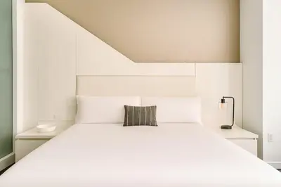 a white bedroom with a white bed with a pillow at W residence in New York