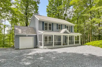 a blue house with a garage in the woods at Boat, Fish and Unwind Waterfront Gem in Pocono Mtns in Lake Ariel