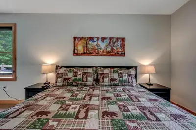 a bedroom with a large bed with two lamps at Tree Haven- fenced yard, hot tub, fire pit in Hawley