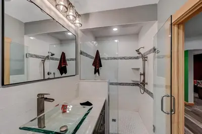 a bathroom with a sink and a shower with a mirror at Tree Haven- fenced yard, hot tub, fire pit in Hawley