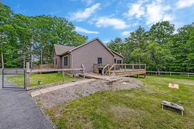 a home with a large deck and a house at Tree Haven- fenced yard, hot tub, fire pit in Hawley