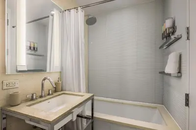 a bathroom with a tub and a sink and a shower at Chic NYC Retreat Beside Broadway & Iconic Sights in New York