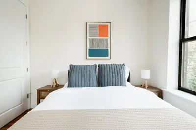 a white bed with two blue pillows in a bedroom at 3BD 2BA in Upper West Side Manhattan! 5 Star Location in New York