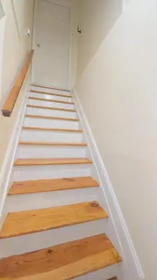 a staircase in a house with white walls and wooden floors at Staten Island Cozy Private 1-br Basement Apt close to NYC Family & Pet Friendly in Willowbrook