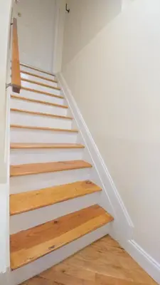 a staircase in a house with white walls and wooden floors at Staten Island Cozy Private 1-br Basement Apt close to NYC Family & Pet Friendly in Willowbrook