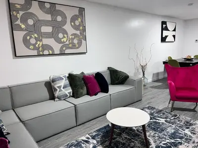 a living room with a gray couch and a pink chair at Exquisite Luxury 3KINGs Bed, 2 Bath in Newark