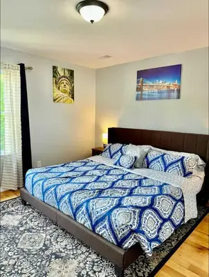 a bedroom with a bed with a blue and white comforter at Cozy Rooms in a Modern and Beautiful Apartment in Irvington