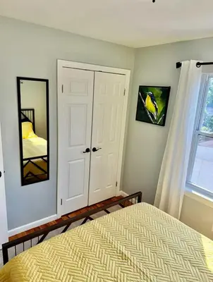 a bedroom with a bed and a mirror and a window at Cozy Rooms in a Modern and Beautiful Apartment in Irvington