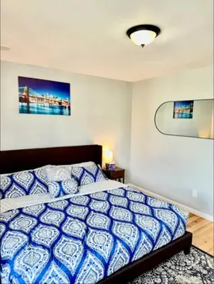 a bedroom with a bed with a blue and white comforter at Cozy Rooms in a Modern and Beautiful Apartment in Irvington