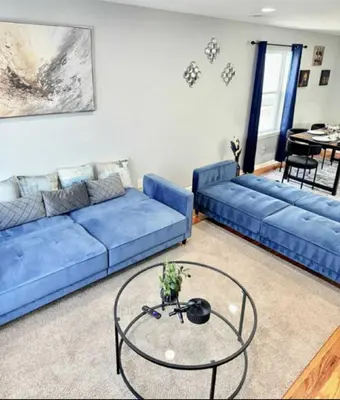 a living room with two blue couches and a glass table at Cozy Rooms in a Modern and Beautiful Apartment in Irvington