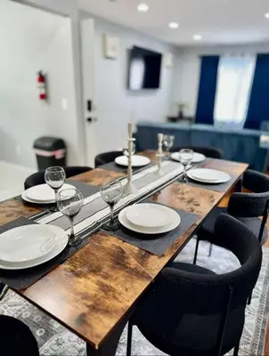 a wooden table with plates and wine glasses on it at Cozy Rooms in a Modern and Beautiful Apartment in Irvington