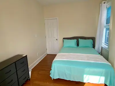 a bedroom with a bed with blue pillows and a dresser at Tropical Oasis - Room 1 in Irvington