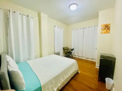 a bedroom with a white bed and a window at Tropical Oasis - Room 1 in Irvington