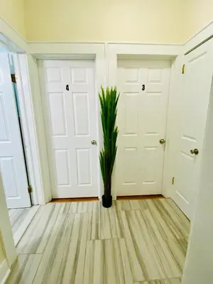 a hallway with two white doors and a potted plant at Tropical Oasis - Room 1 in Irvington