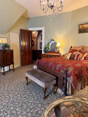 a bedroom with a bed and a chair and a table at The Stegmaier Mansion Guest House in Wilkes-Barre