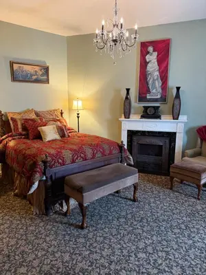 a bedroom with a bed and a fireplace and a chandelier at The Stegmaier Mansion Guest House in Wilkes-Barre