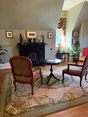 a living room with two chairs and a table and a fireplace at The Stegmaier Mansion Guest House in Wilkes-Barre