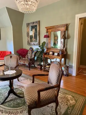 a living room with chairs and a table and a mirror at The Stegmaier Mansion Guest House in Wilkes-Barre