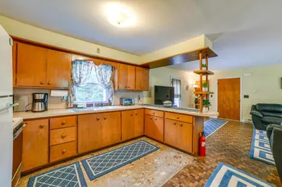 a large kitchen with wooden cabinets and a couch at Serene Duplex with On-Site Brook in Callicoon Center in Roscoe